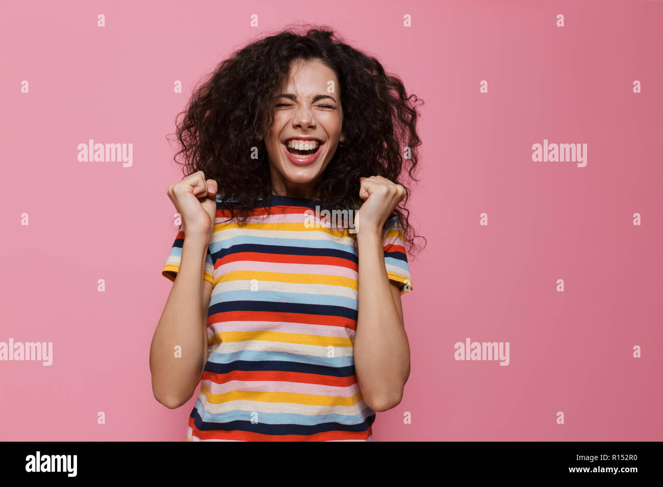 Image femme 20s avec les cheveux bouclés de rire et de joie au fil isolé sur fond rose Banque D'Images