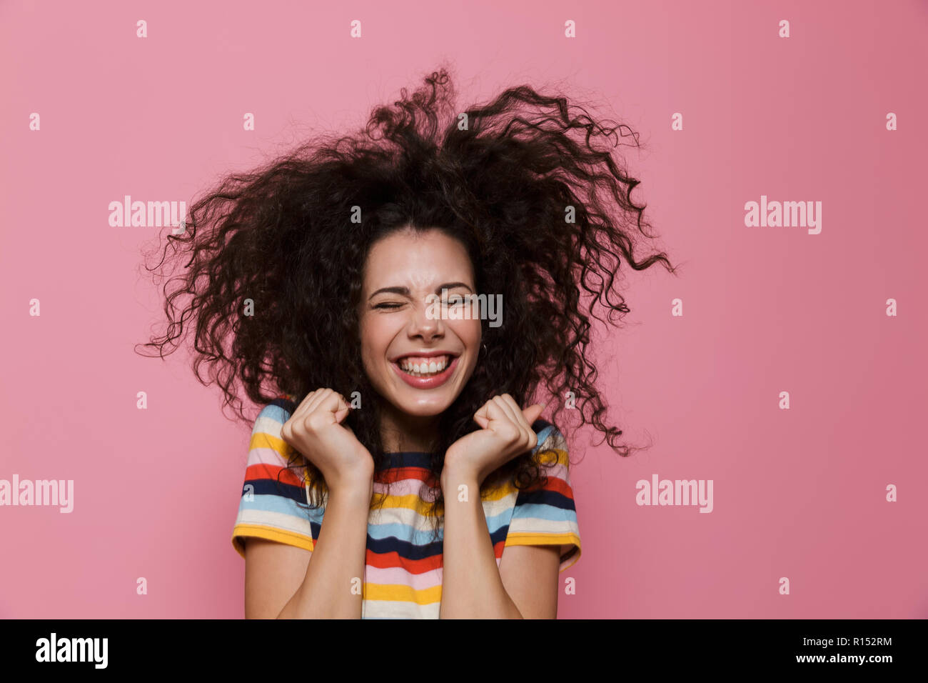 Image de femme joyeuse 20s avec les cheveux bouclés se réjouir et isolé sur fond rose sourire Banque D'Images