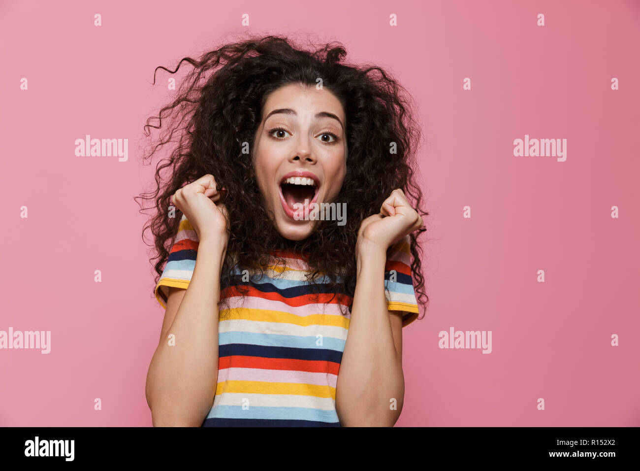 Image de femme étonné 20s avec les cheveux bouclés se réjouir et crier plus isolé sur fond rose Banque D'Images