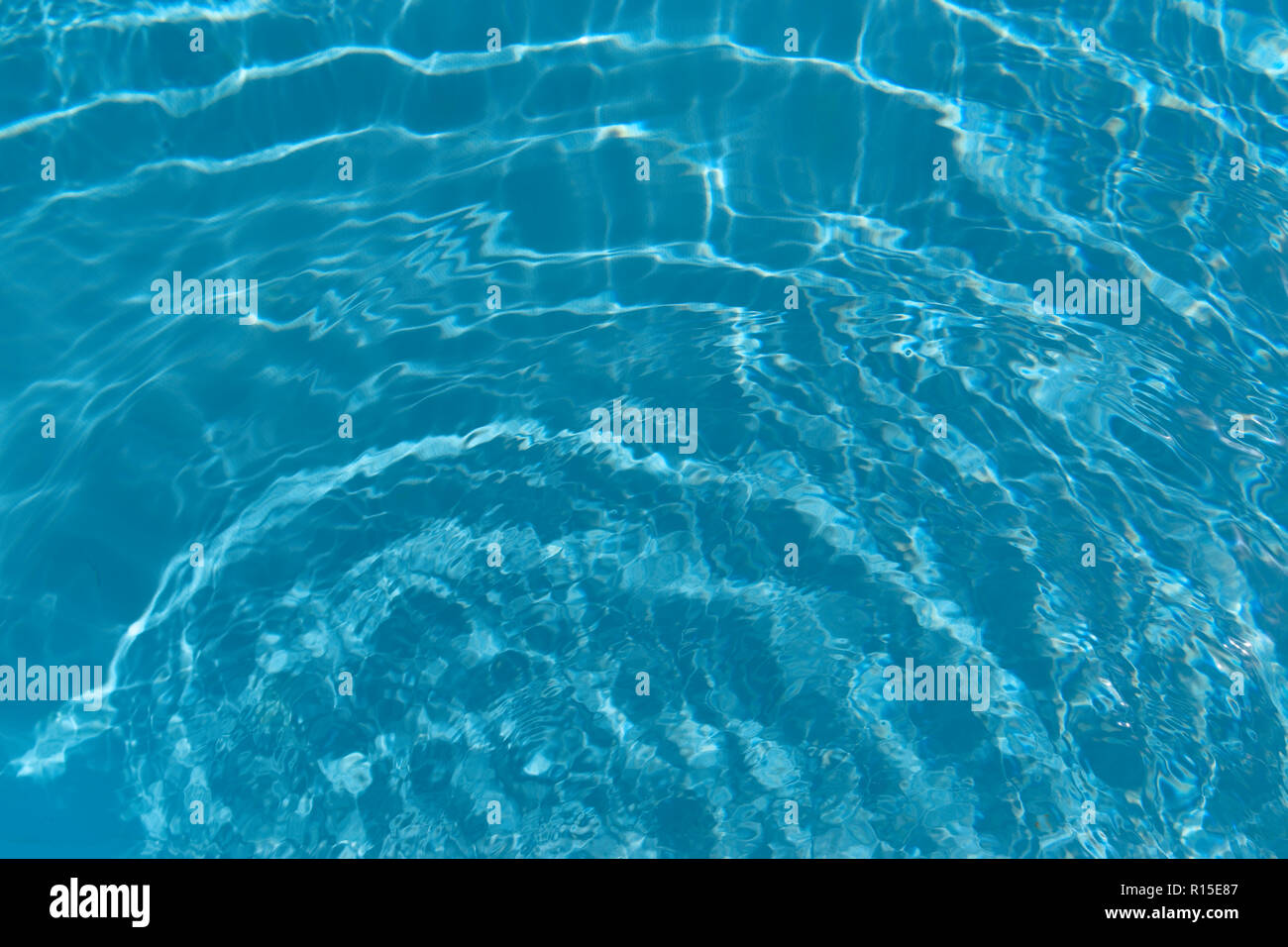Tour des vagues dans l'eau bleue et claire de piscine Banque D'Images