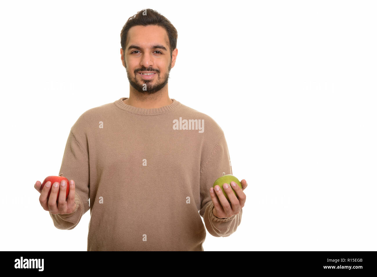 Young happy Indian man holding red et green apple Banque D'Images