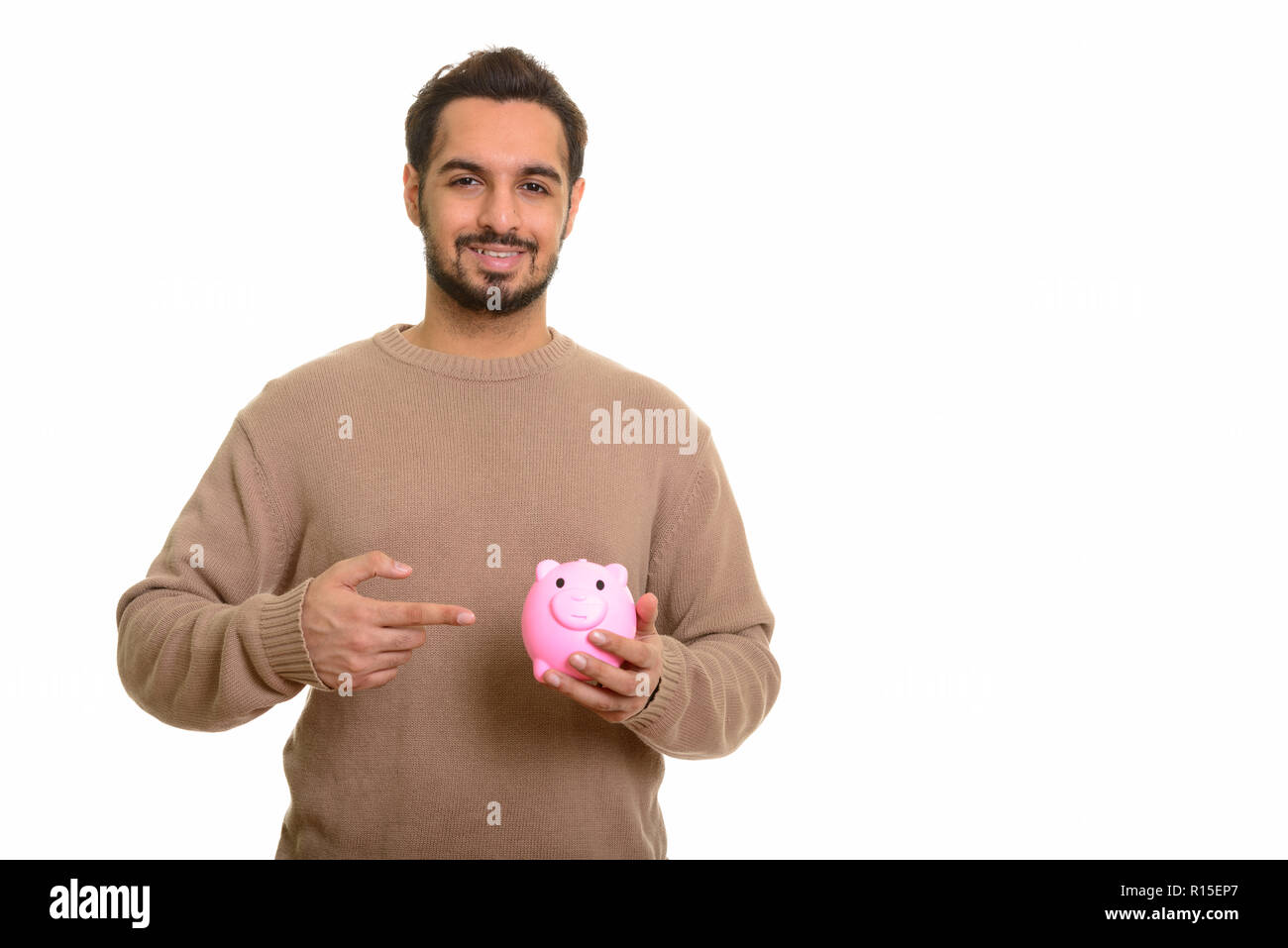 Young happy Indian man holding piggy bank et montre de l'index Banque D'Images