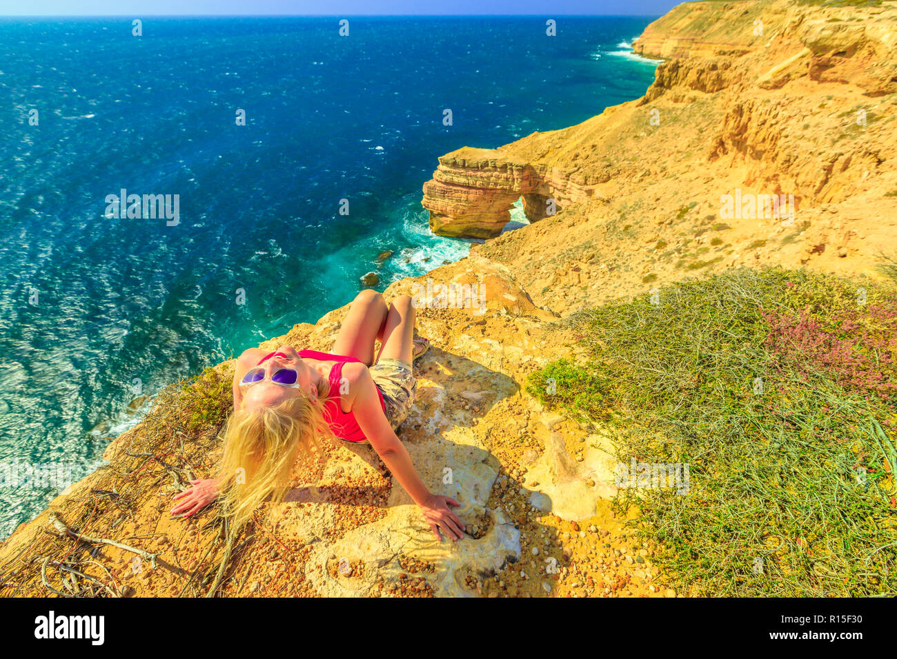 Femme blonde aime le pont naturel dans le Parc National de Kalbarri, dans l'ouest de l'Australie. Backpacker girl sur falaises pittoresques du littoral de l'Océan Indien. Billet d'Outback australien. Ciel bleu, soleil d'été Banque D'Images