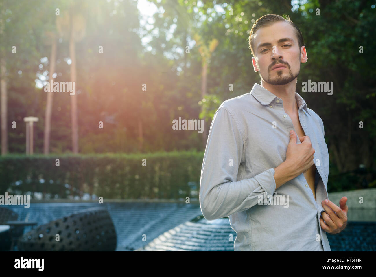 Portrait de jeune homme élégant barbu en plein air avec des reflets Banque D'Images