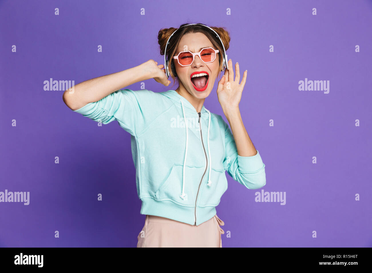 Portrait d'une jeune fille avec un miroir lumineux violet plus isolés, écouter de la musique avec des écouteurs, la danse Banque D'Images