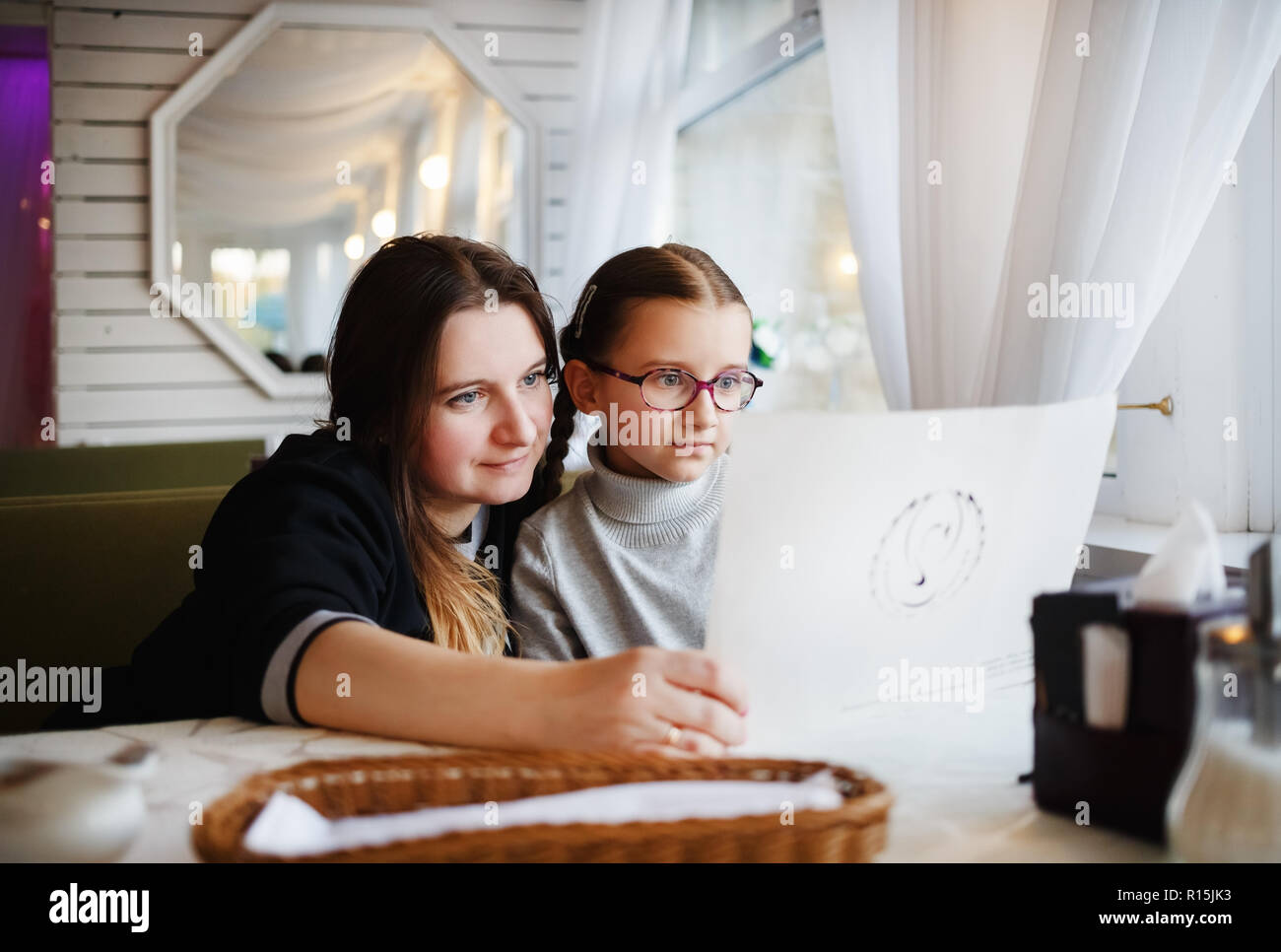 Famille dans un restaurant. Mère et fille à la recherche au menu du restaurant. Focus sélectif. Banque D'Images