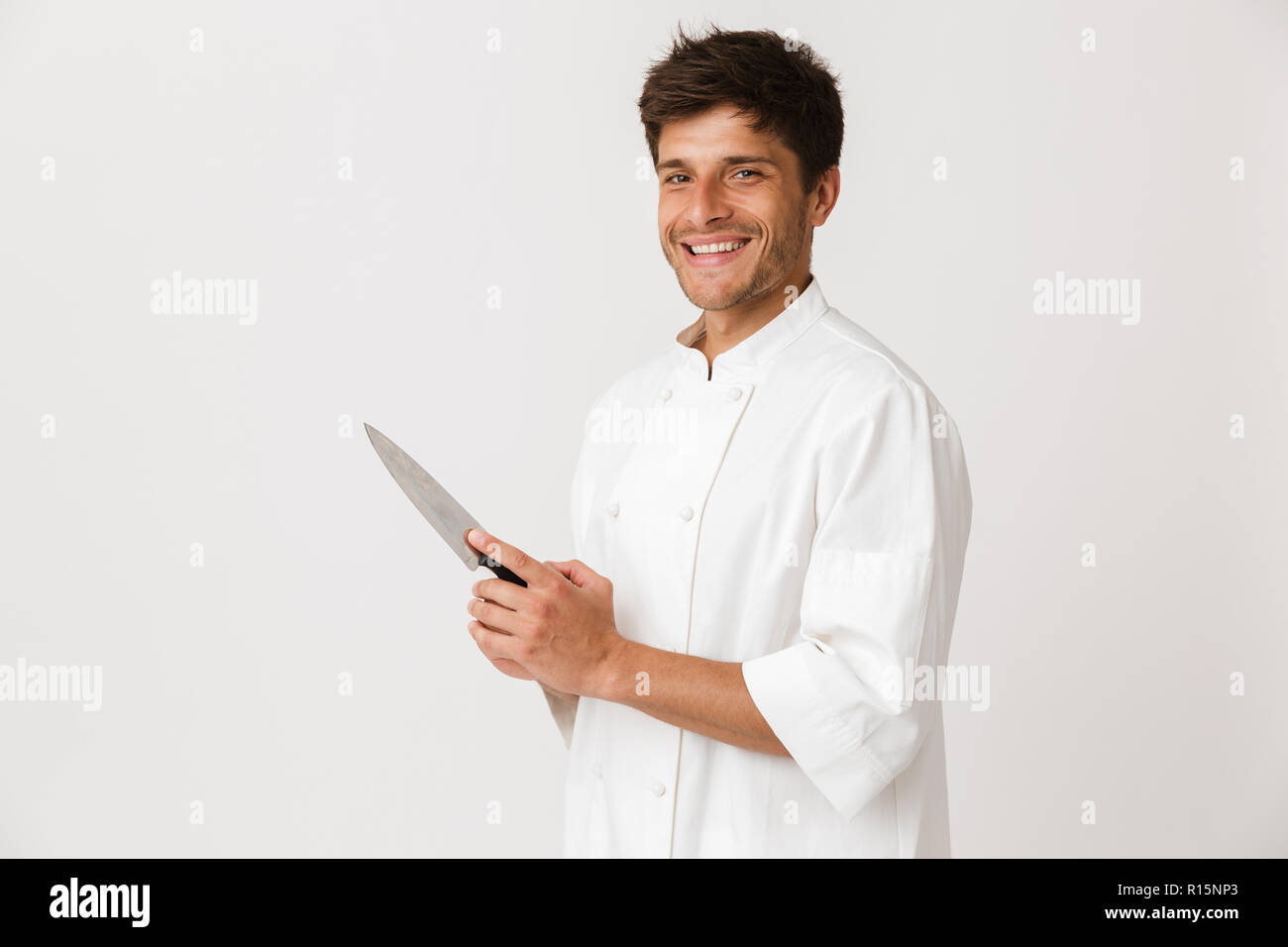 Image de beau jeune homme debout chef isolated over white wall background holding couteau. Banque D'Images