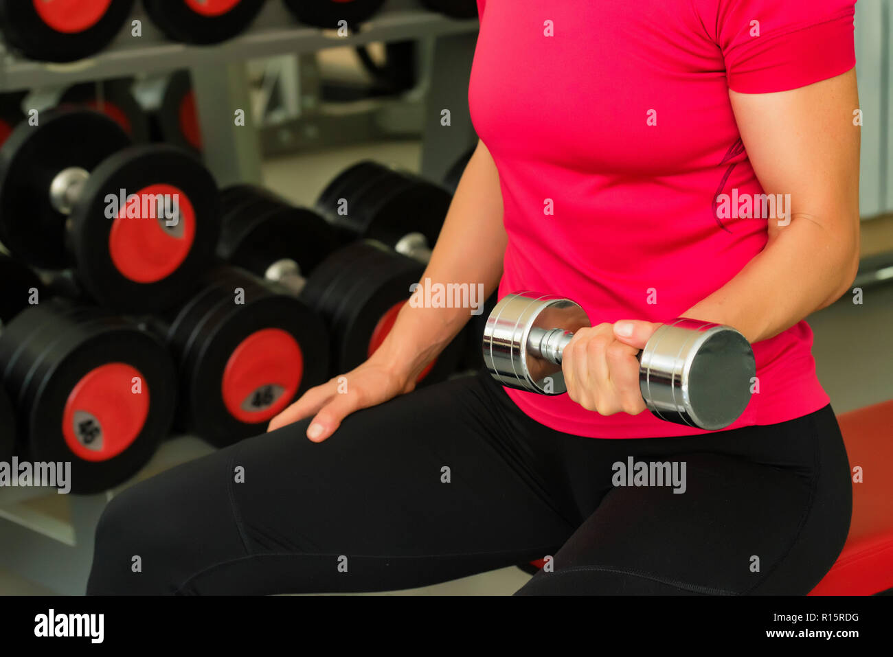 Jeune femme dans la salle de sport moderne biceps trains Banque D'Images
