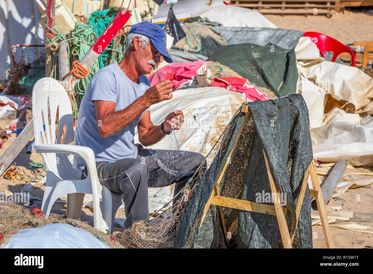 Le pêcheur local qui tend ses filets de pêche sur la plage de Monte Gordo, Algarve, Portugal Banque D'Images