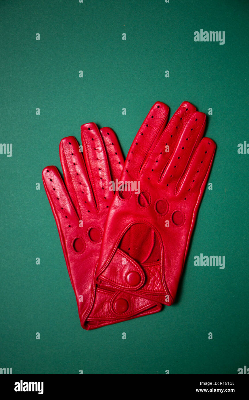 Gants rouge vif avec des trous sur un fond vert Banque D'Images