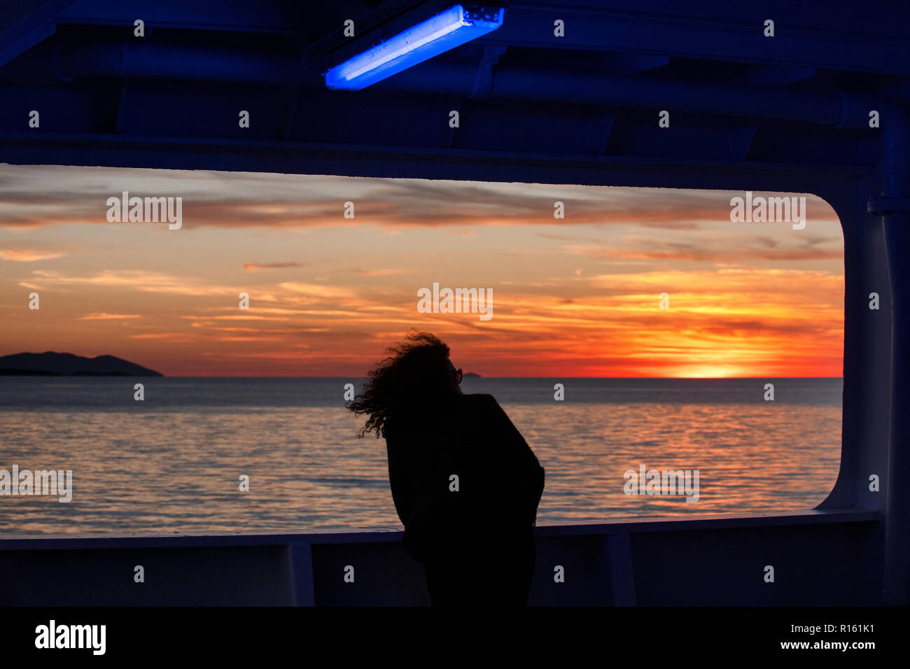 Une femme aime coucher de soleil sur l'île de Hvar, Croatie dans la mer Adriatique depuis le pont d'un ferry Jadrolinija, en route vers le produit déversé sur le continent. Banque D'Images