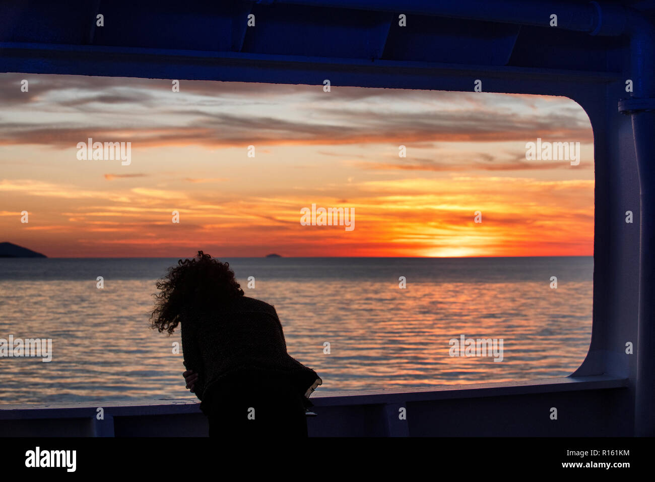 Une femme aime coucher de soleil sur l'île de Hvar, Croatie dans la mer Adriatique depuis le pont d'un ferry Jadrolinija, en route vers le produit déversé sur le continent. Banque D'Images