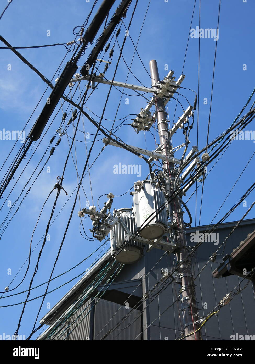 Scène de rue avec une masse d'emmêler les fils et les câbles en haut d'un pylône d'électricité, Kyoto, Japon ; câblage souterrain n'est pas commune. Banque D'Images