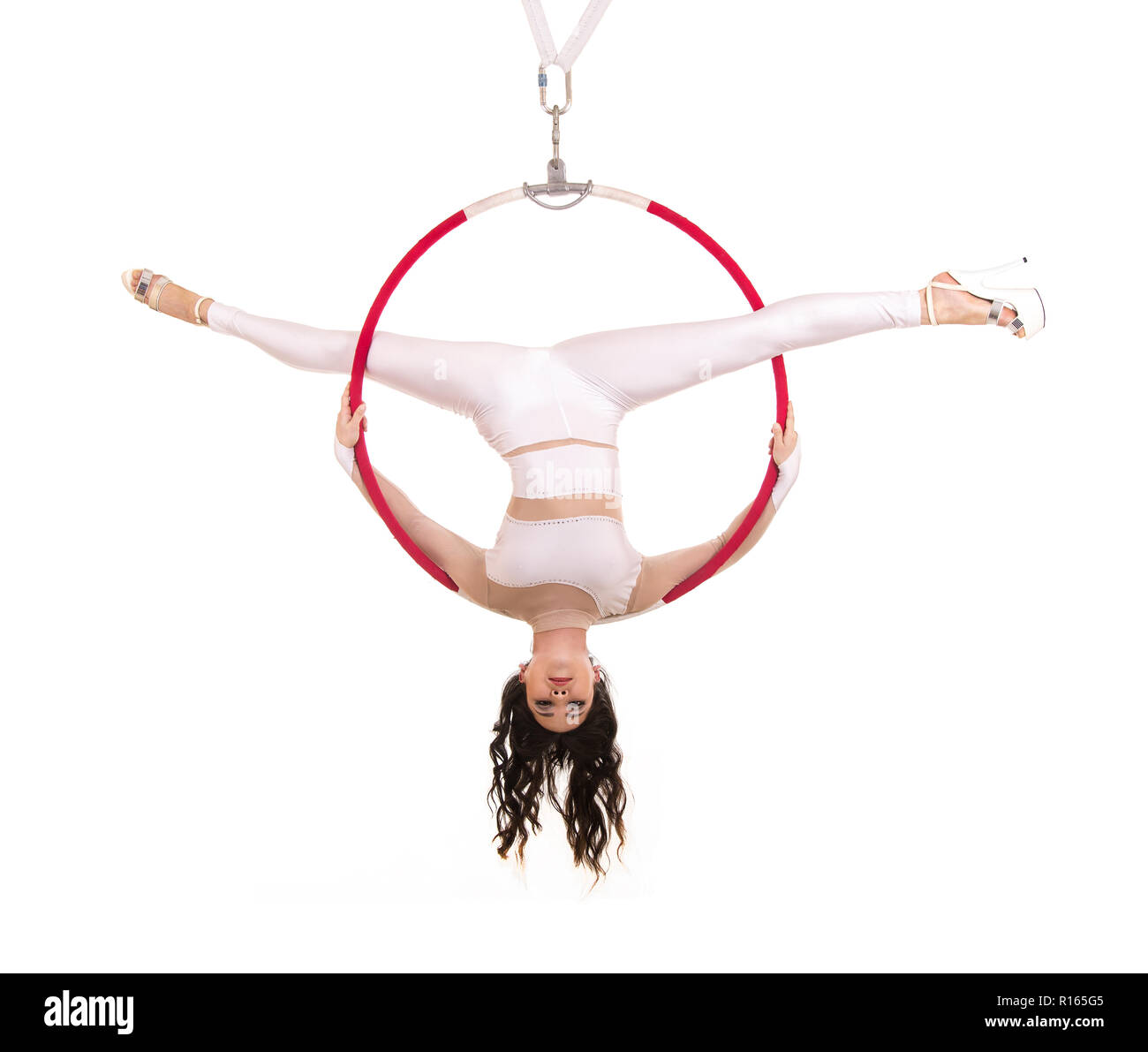 Une jeune femme exécute les éléments acrobatiques dans l'anneau d'air. Des performances en studio sur fond blanc. Banque D'Images