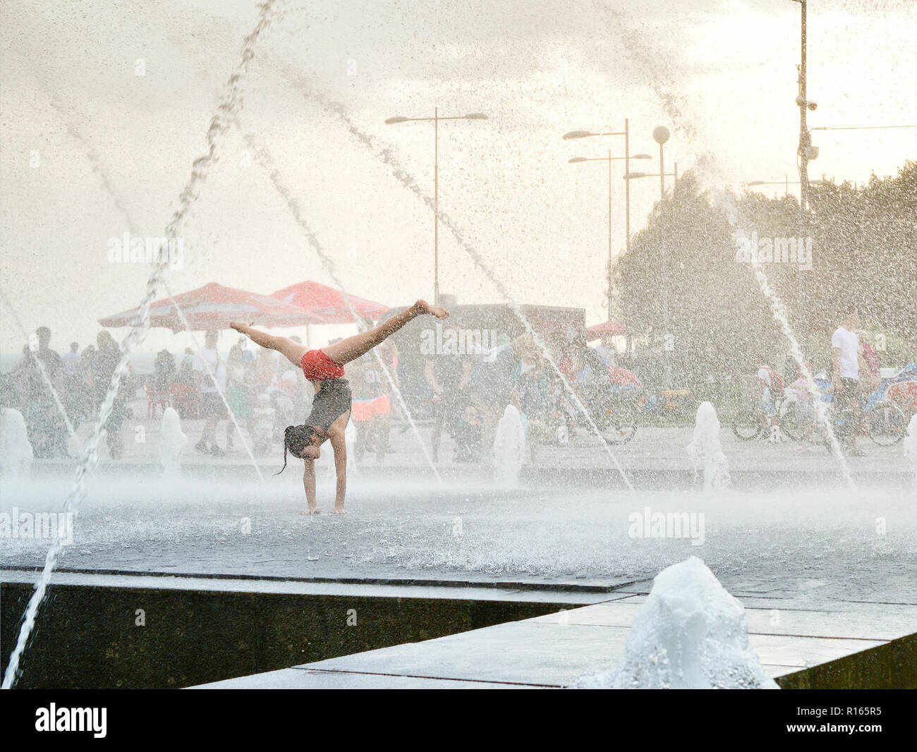 La jeune fille joue dans la fontaine d'eau, l'exécution de numéros acrobatiques. Banque D'Images