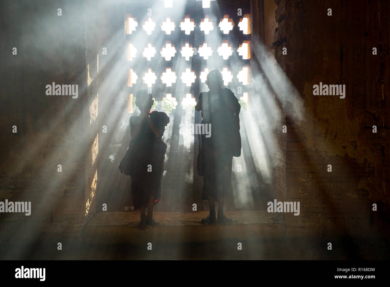 Silhouette de deux jeunes moines priant à l'intérieur de la pagode bouddhiste Temple de Bagan, Myanmar Banque D'Images