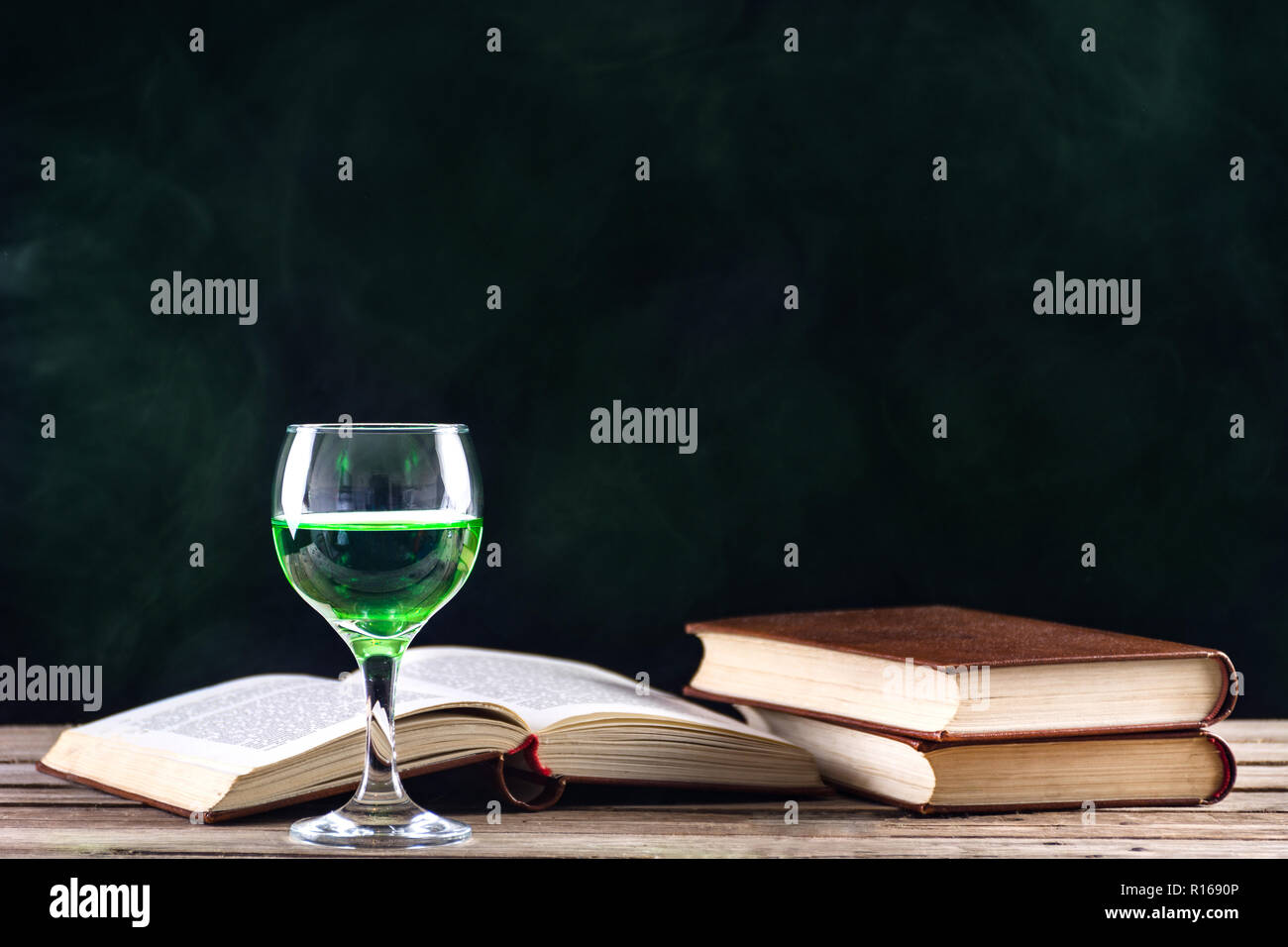 Absinthe Fée Verte ou boire de l'inspiration et muse d'écrivains et  d'artistes. Verre sur table en bois rétro et des livres. Smoky vert fond  sombre Photo Stock - Alamy