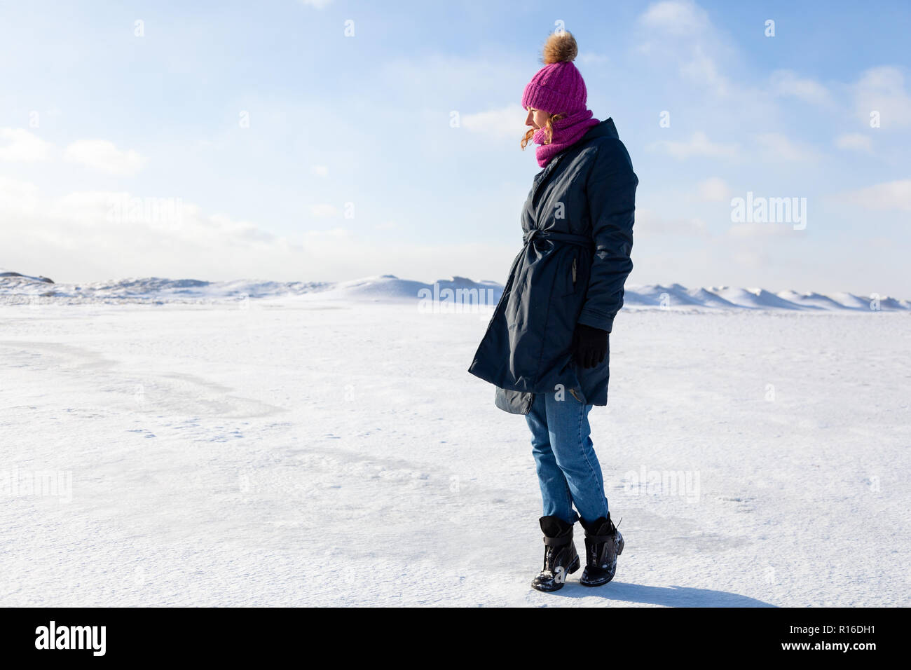 Une jeune femme en tricot rose chapeau, manteau noir jouit de la nature de  l'hiver, marchant sur la mer gelée au pôle nord autour de ciel bleu en  hiver frosty Photo Stock -