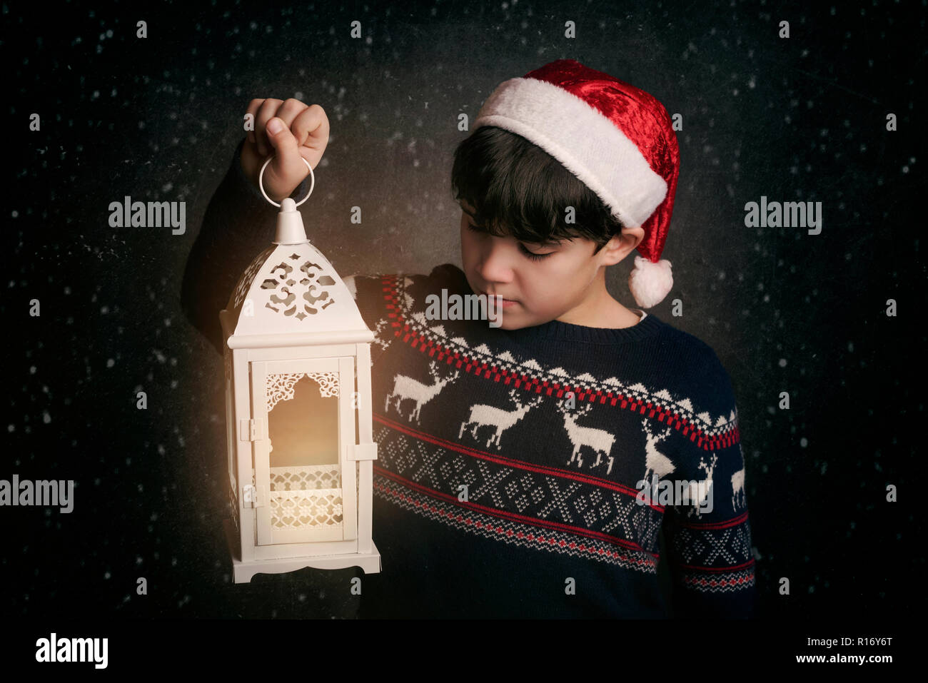 Little Boy holding une vieille lampe sur fond noir Banque D'Images