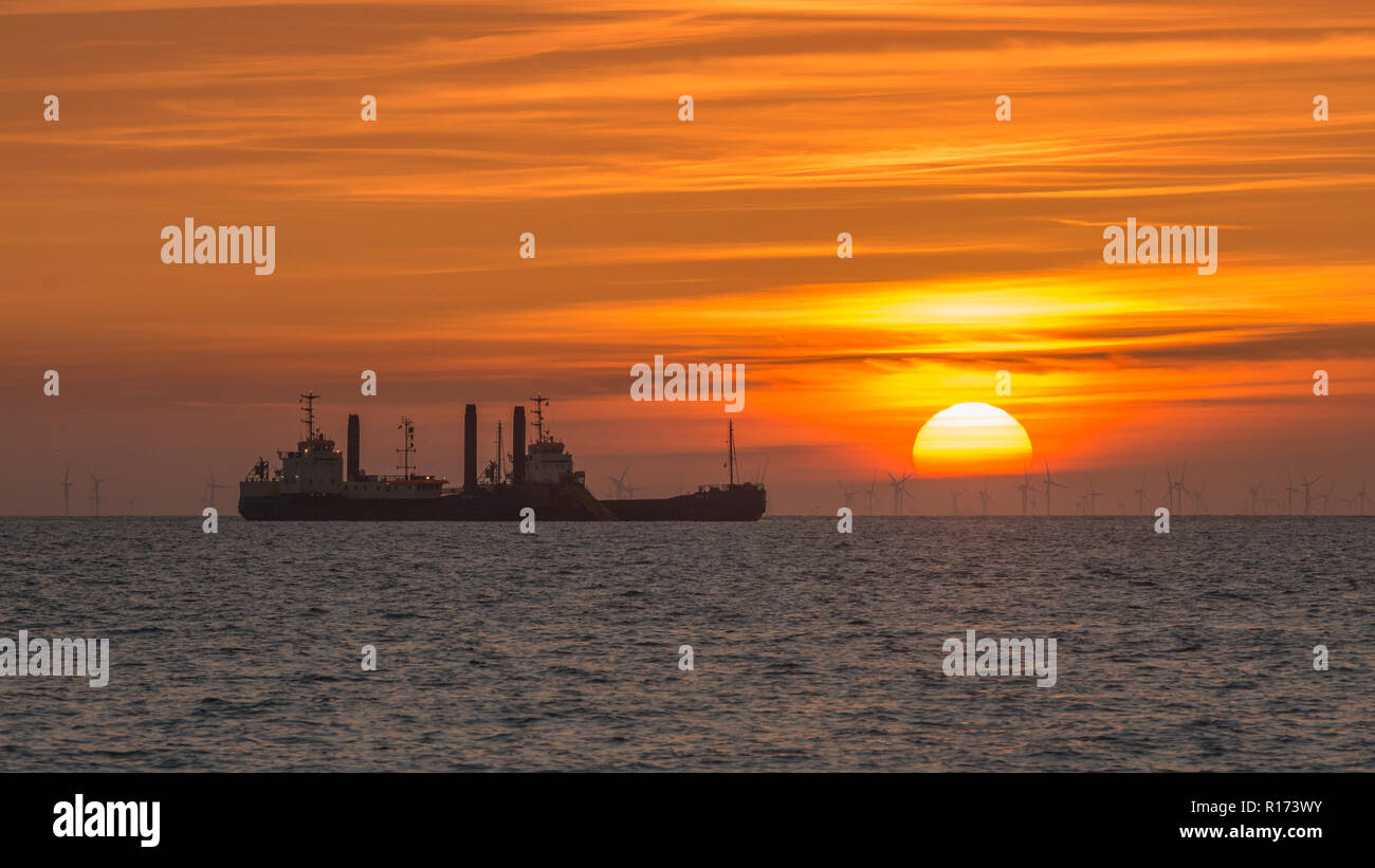 Navire de dragage en mer au coucher du soleil Banque D'Images