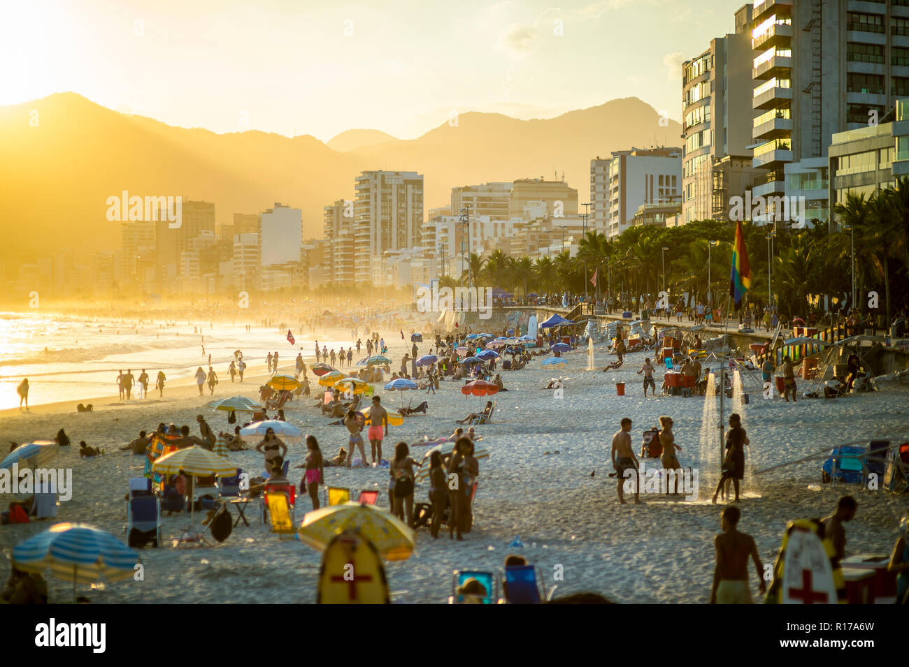 RIO DE JANEIRO - circa 2018, février : jeunes douche sous une gay pride drapeau arc-en-ciel au coucher du soleil au-dessus de la plage d'Ipanema, Banque D'Images