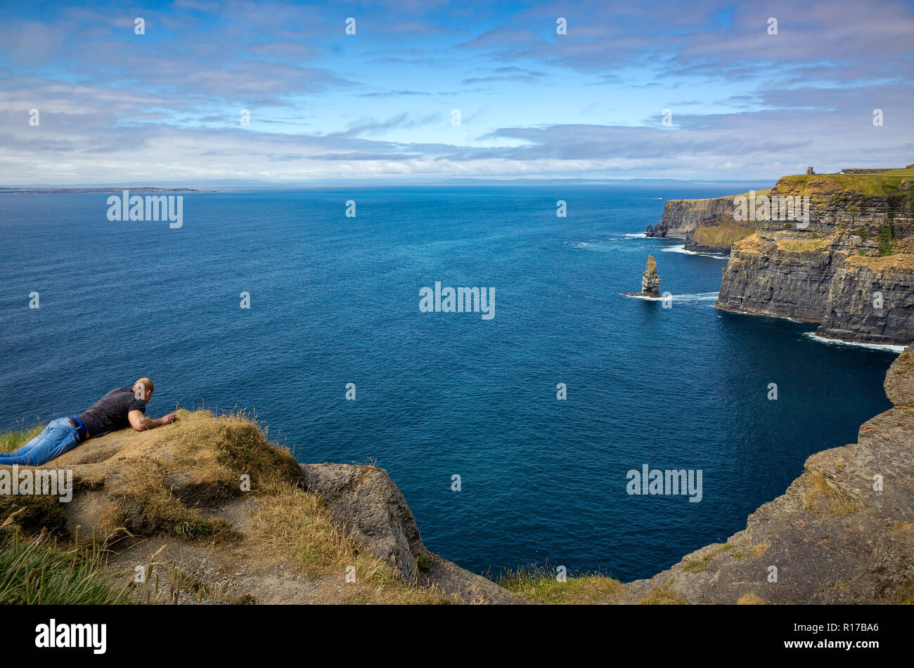 Homme protrudicing dangereusement sur les falaises de Moher, le Burren, comté de Clare, Irlande Banque D'Images