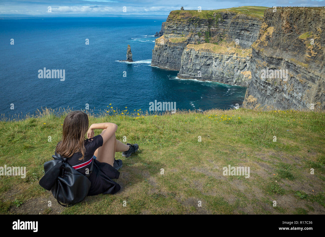 Jeune fille tout en relaxant sur la falaise, assis sur des falaises de Moher, comté Clare, Irlande Banque D'Images