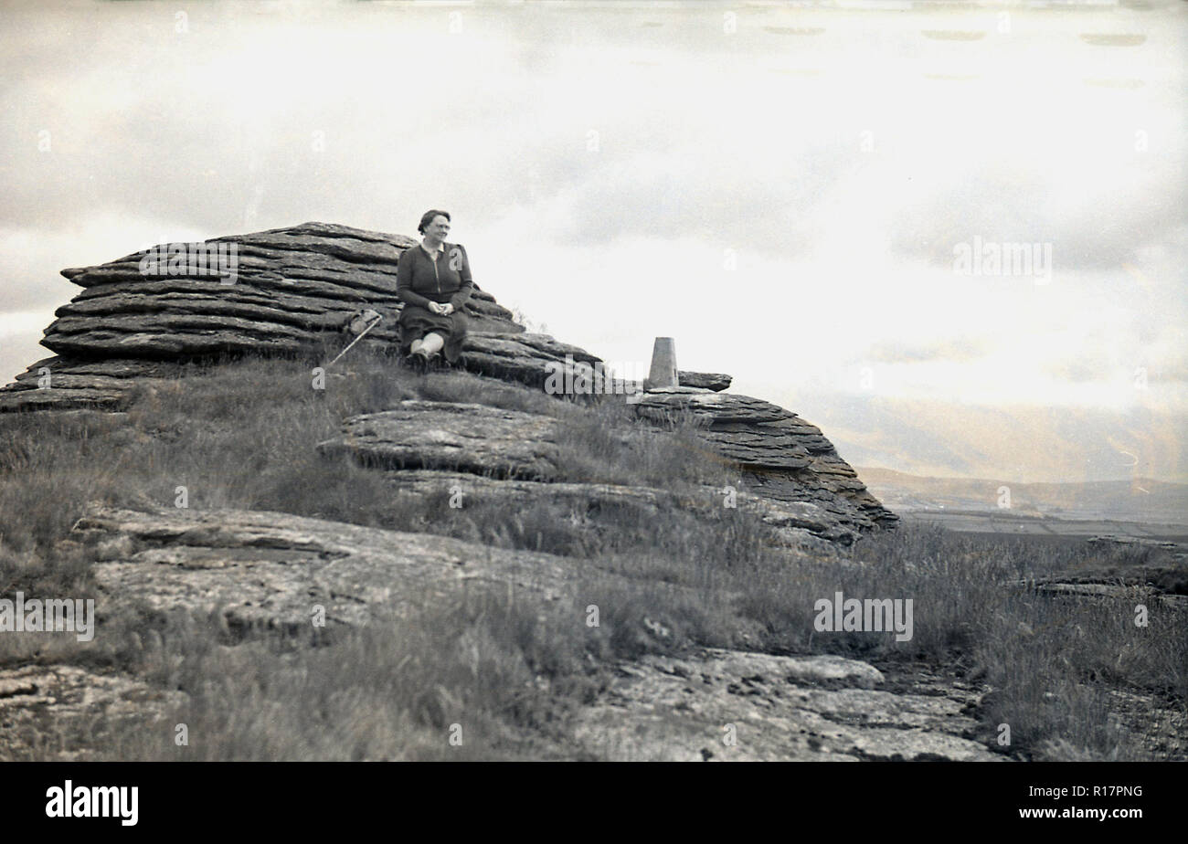 Années 1950, historique, un tor ou craig, Exmoor, England, UK, une dame walker assis sur le côté de la crête rocheuse. Banque D'Images