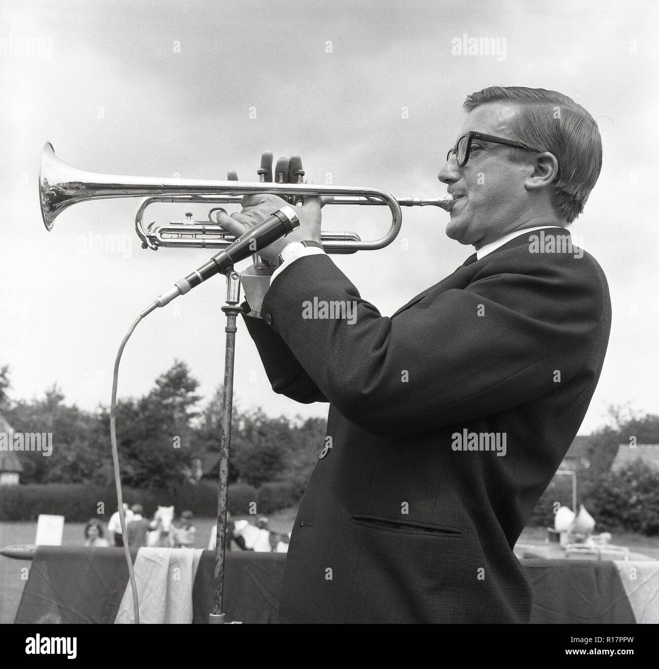 1967, photo historique montrant Roy Castle le légendaire musicien, artiste, et présentateur de télévision, peut-être le plus célèbre pour la présentation de la série TV pour enfants, 'Record Breakers", effectuant à l'extérieur à jouer de la trompette à une fête d'été, Buckinghamshire, Angleterre, Royaume-Uni. Banque D'Images