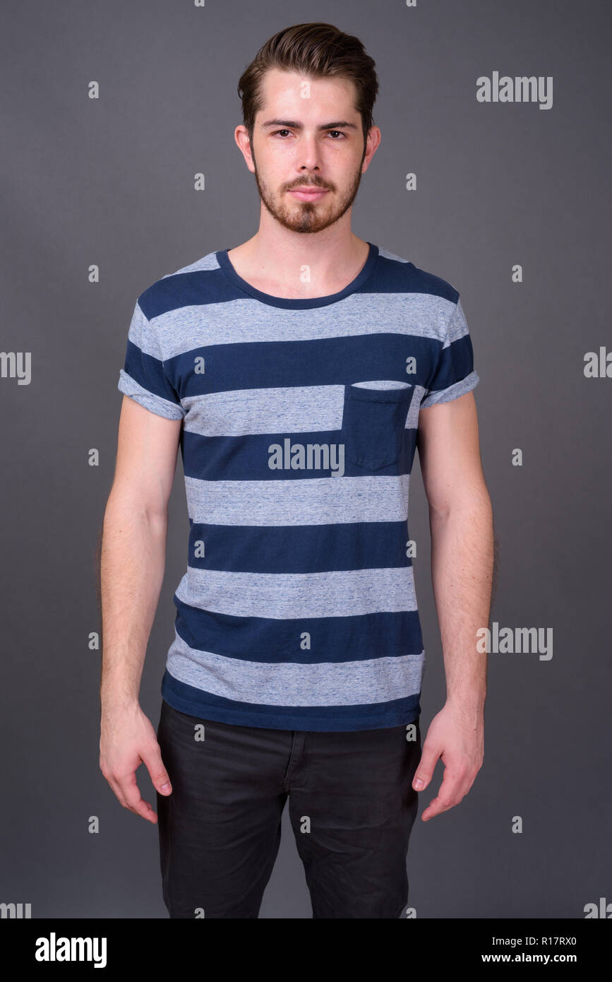 Beau jeune homme barbu contre l'arrière-plan gris Banque D'Images