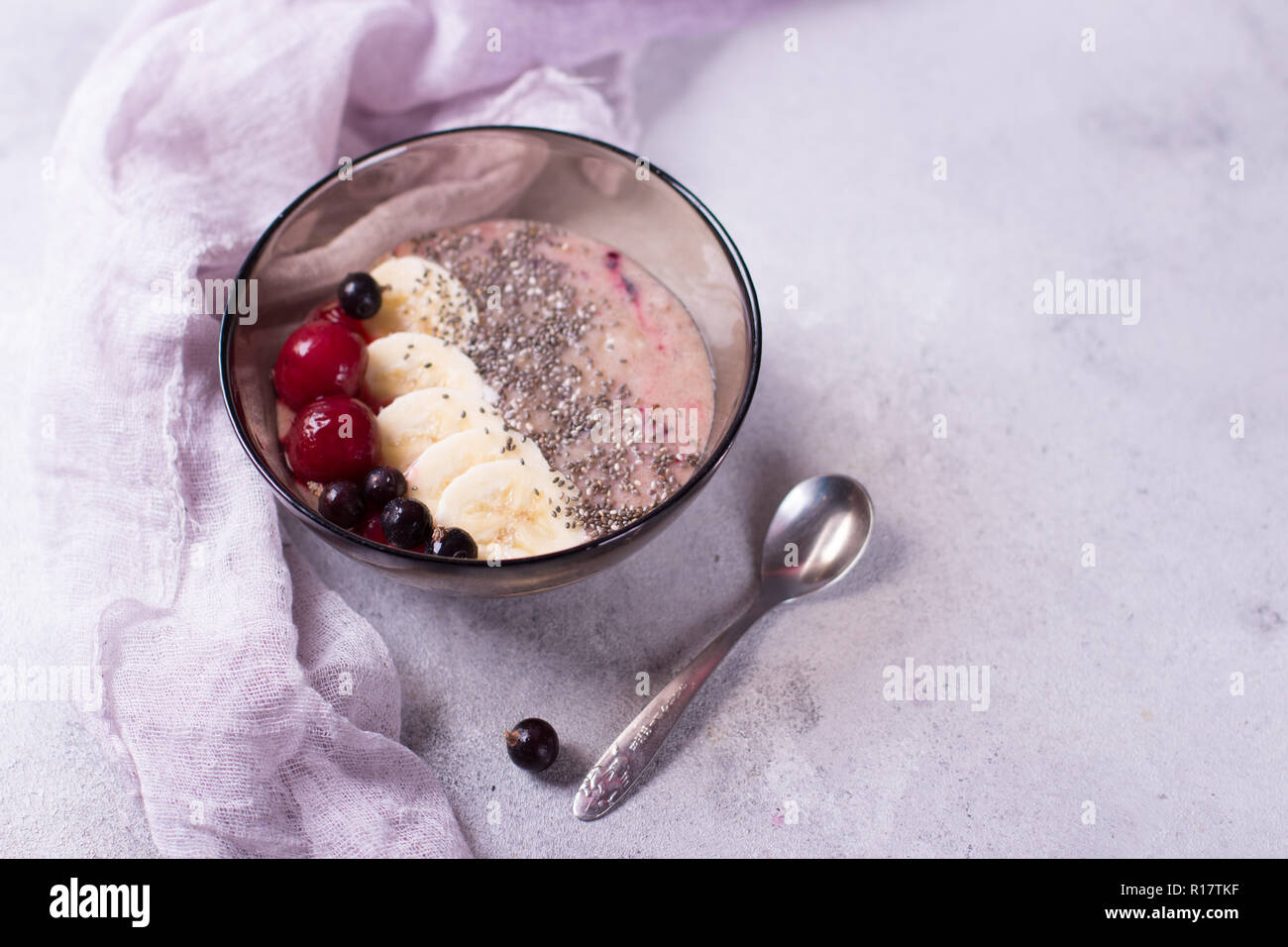 Smoothy savoureux pour le petit-déjeuner avec chia sur fond violet et violet avec banane, cerise, cassis et Banque D'Images