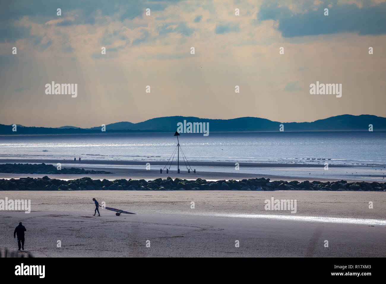 Plage vide sur un sombre jour Moody. Un homme tire sur un kayak retour à la plage. Prise à Prestatyn, dans le Nord du Pays de Galles, Royaume-Uni, 2018 Banque D'Images