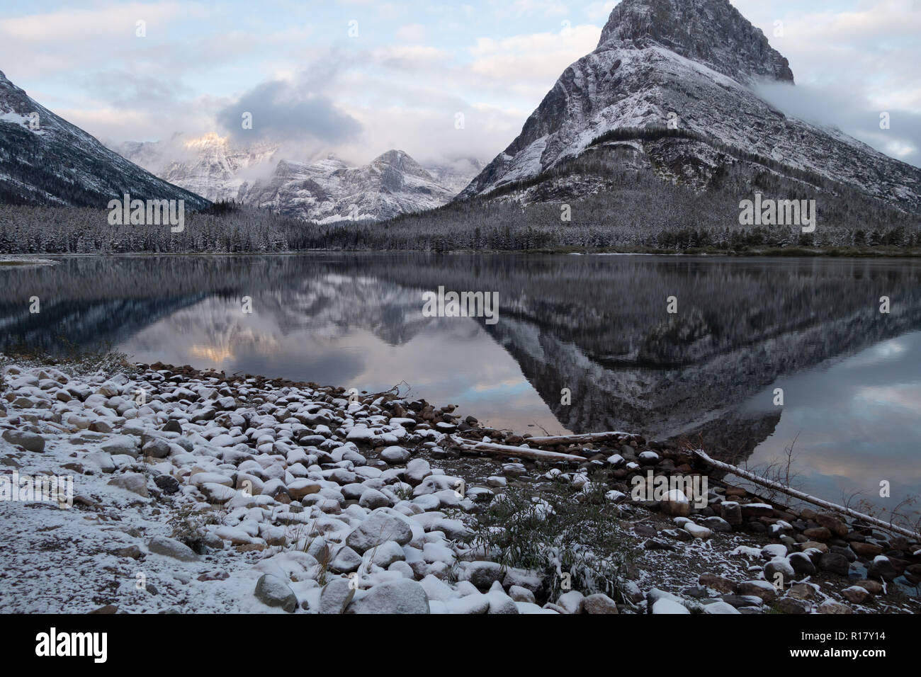 Mt Grinnell reflète dans Swiftcurrent Lake au début de l'aube lumière après une tempête de neige. Le Glacier National Park, Montana Banque D'Images