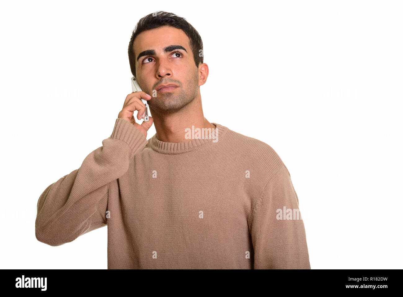 Beau jeune homme perse parlant au téléphone tout en pensant Banque D'Images