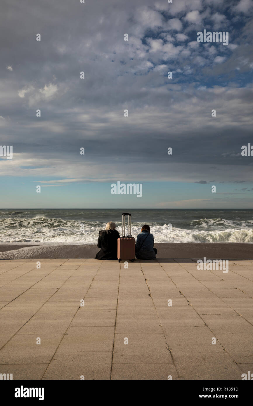 Deux femme assise sur le front de mer, séparés par leur assurance, face à la mer. Banque D'Images