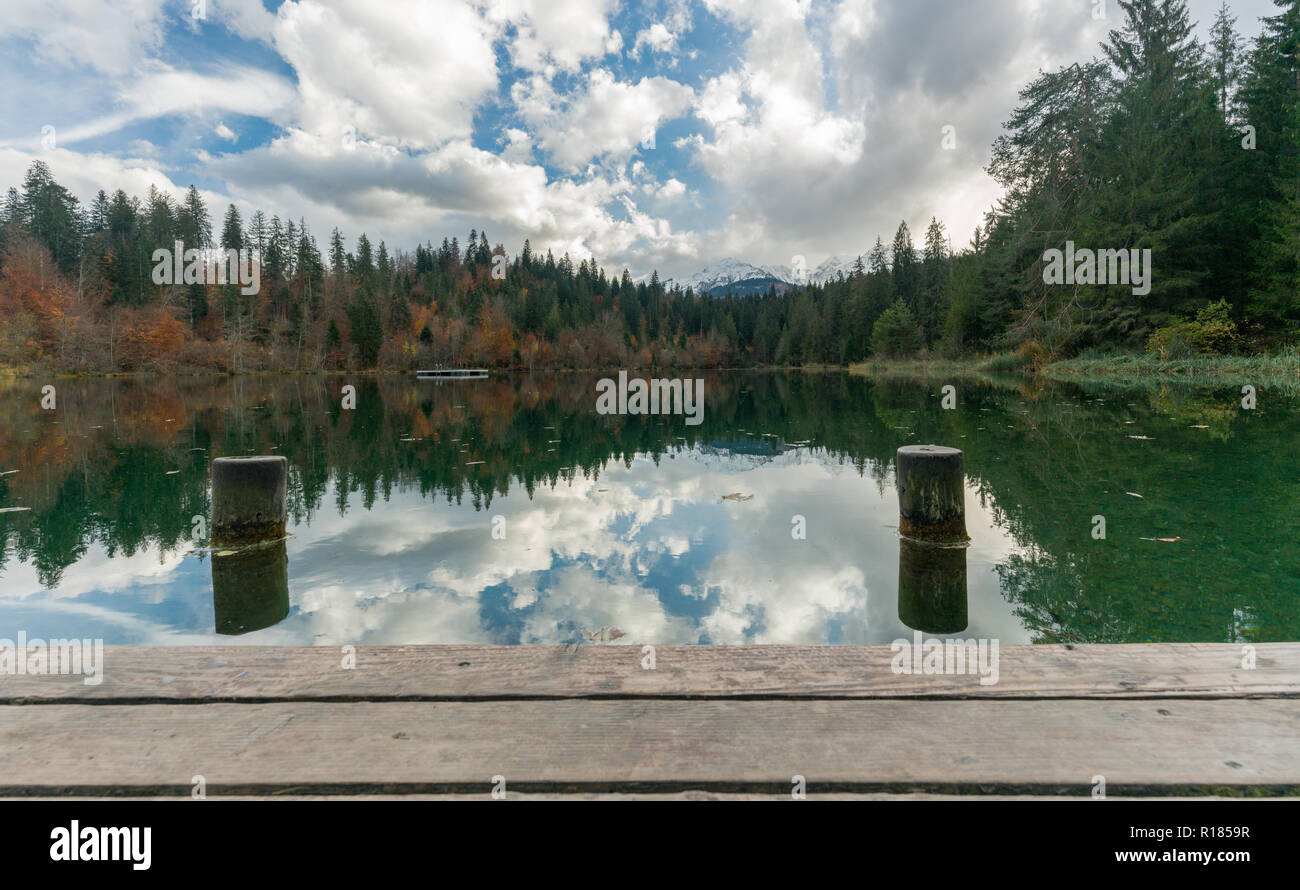 Jetée en bois et promenade avec pylônes dock sur le bord d'un lac de montagne idyllique entouré de forêt couleur d'automne Banque D'Images