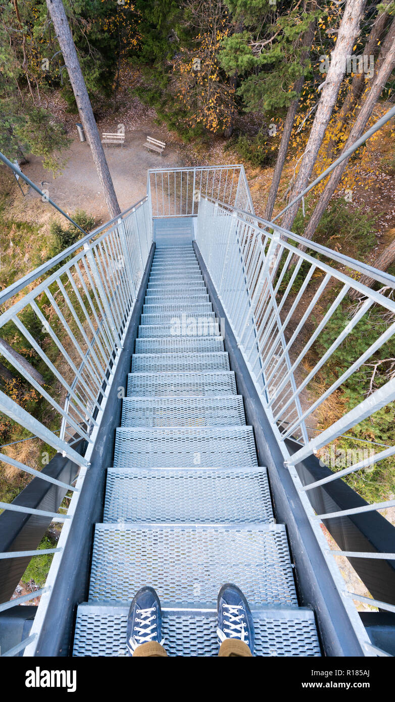 Metal escaliers menant en forêt depuis une plate-forme d'observation avec pieds mâles en bleu chaussures dans l'avant-plan Banque D'Images