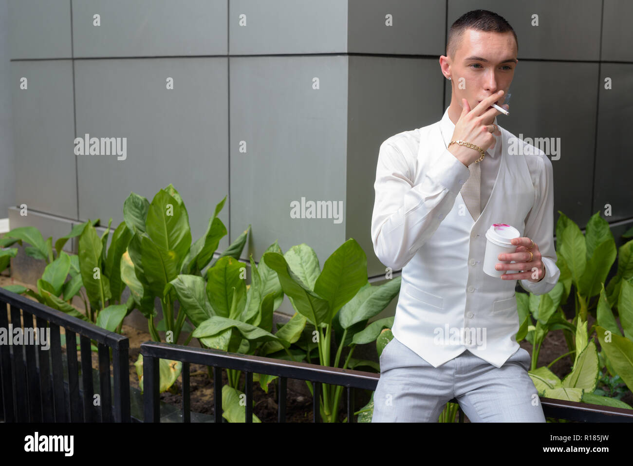 Les jeunes homosexuels homme androgyne LGTB de boire du café et fumer cigarette Banque D'Images