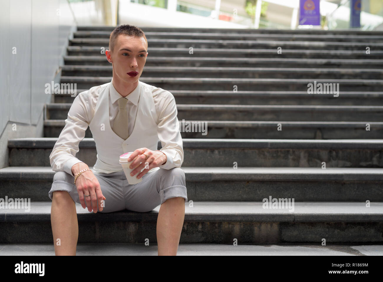 Les jeunes LGBT homosexuel androgyne businessman sitting on stairs Banque D'Images