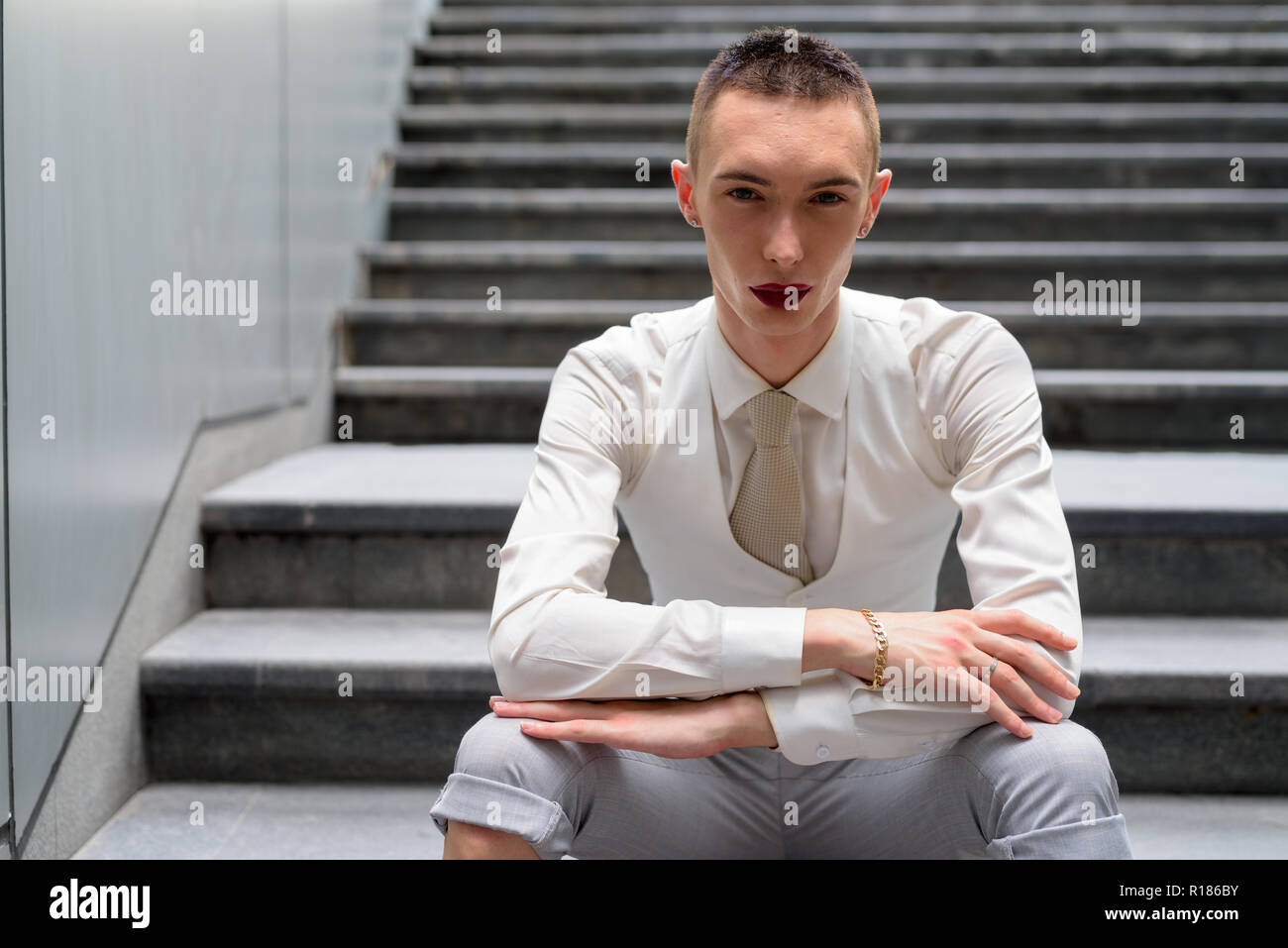 Les jeunes LGBT homosexuel androgyne businessman sitting on stairs Banque D'Images