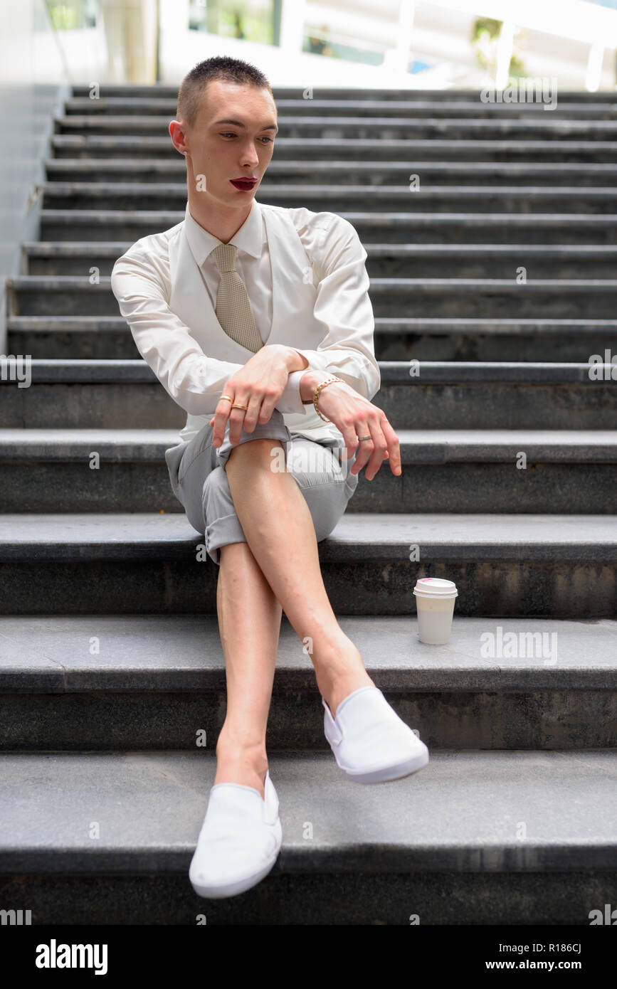 Les jeunes LGBT homosexuel androgyne businessman sitting on stairs Banque D'Images