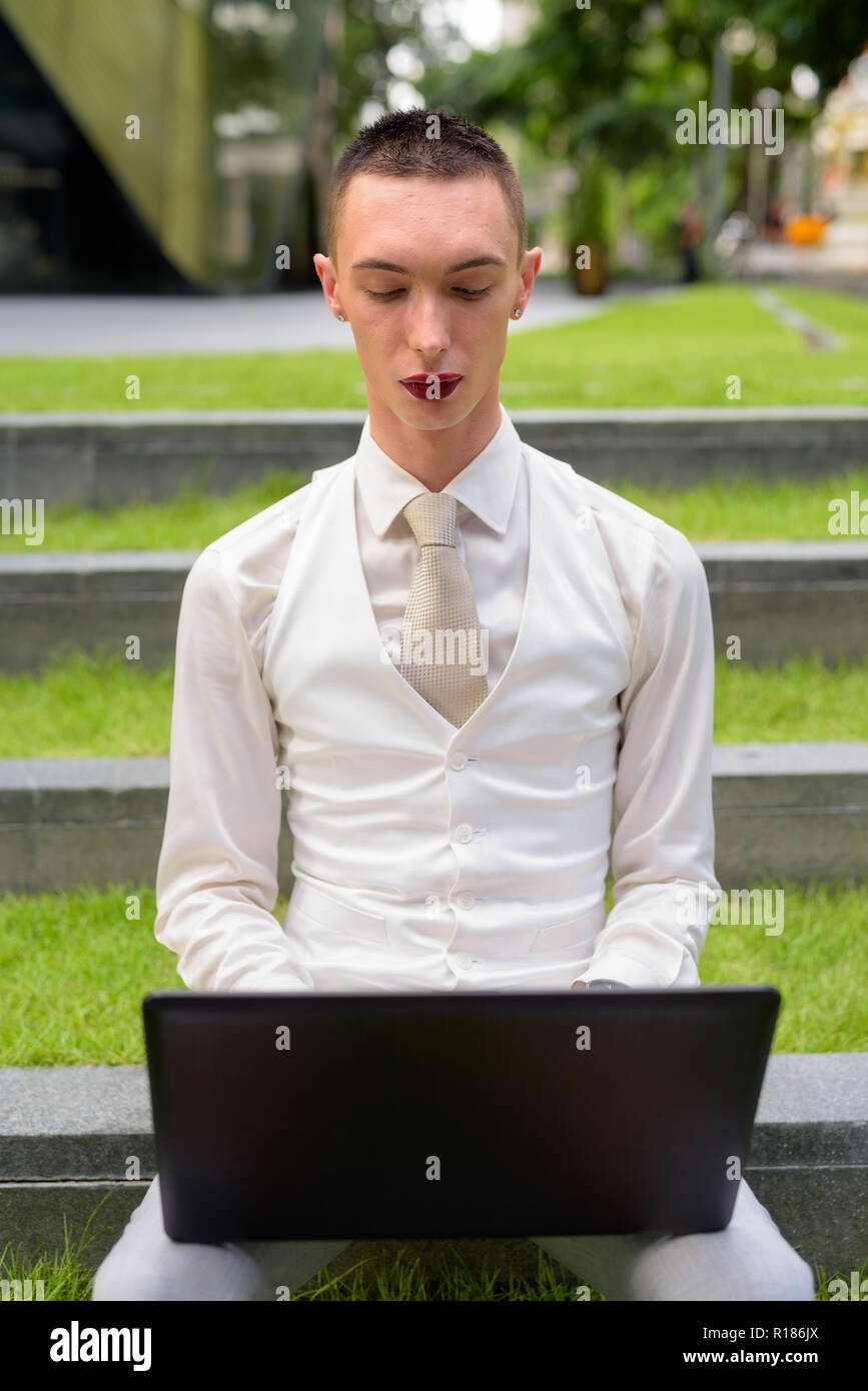 LGTB businessman sitting on stairs while using laptop computer Banque D'Images