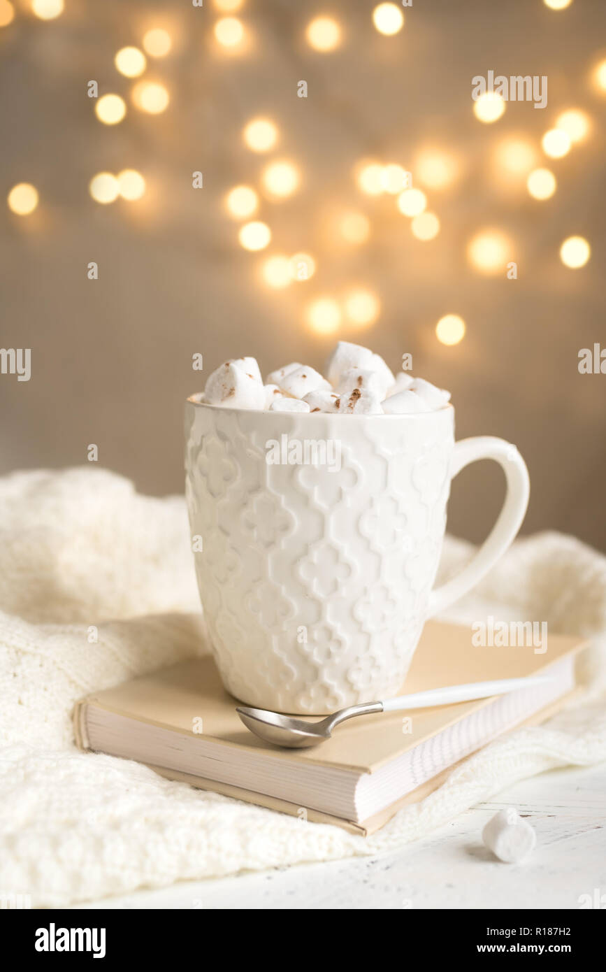 Chocolat chaud avec des guimauves en blanc mug, copiez l'espace. Boisson cacao chaud pour Noël et les vacances d'hiver, avec écharpe, phares sur tableau blanc. Banque D'Images