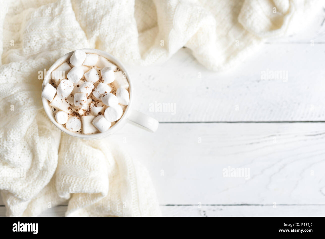 Chocolat chaud avec des guimauves en blanc mug, vue du dessus, copiez l'espace. Boisson cacao chaud pour Noël et vacances d'hiver avec l'écharpe sur le tableau blanc. Banque D'Images