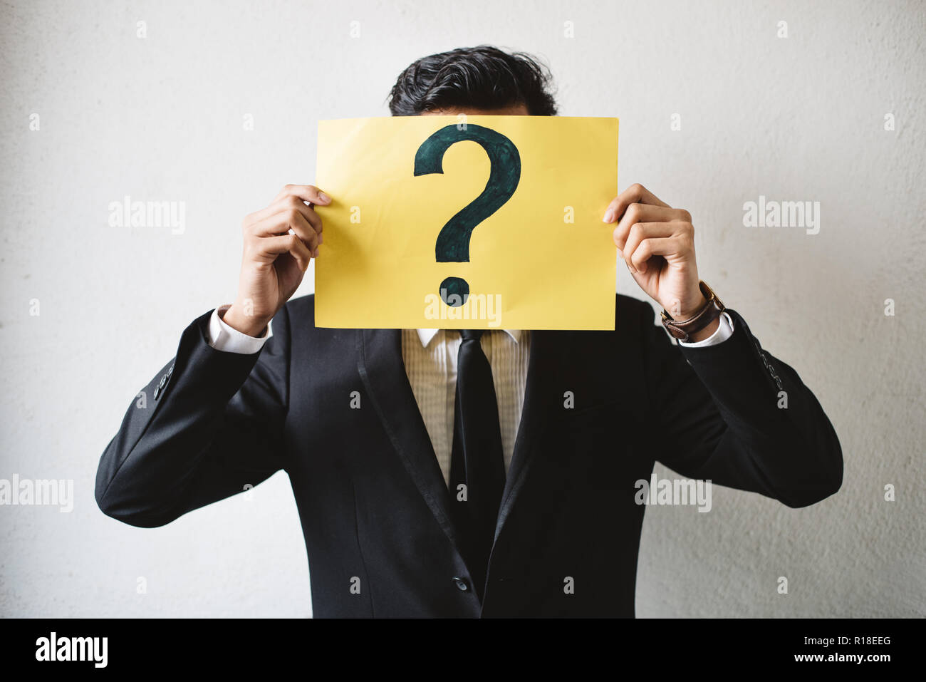 Young adult asian businessman holding pancarte jaune papier avec point d'interrogation. Notion d'entreprise FAQ et questions Banque D'Images