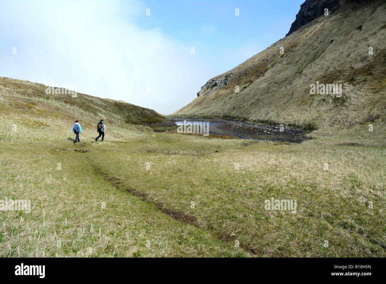 Deux peuples Unangan (Aleut) les jeunes de la randonnée le long d'un ancien sentier dans les montagnes de Unalaska, Îles Aléoutiennes, Alaska, United States. Banque D'Images