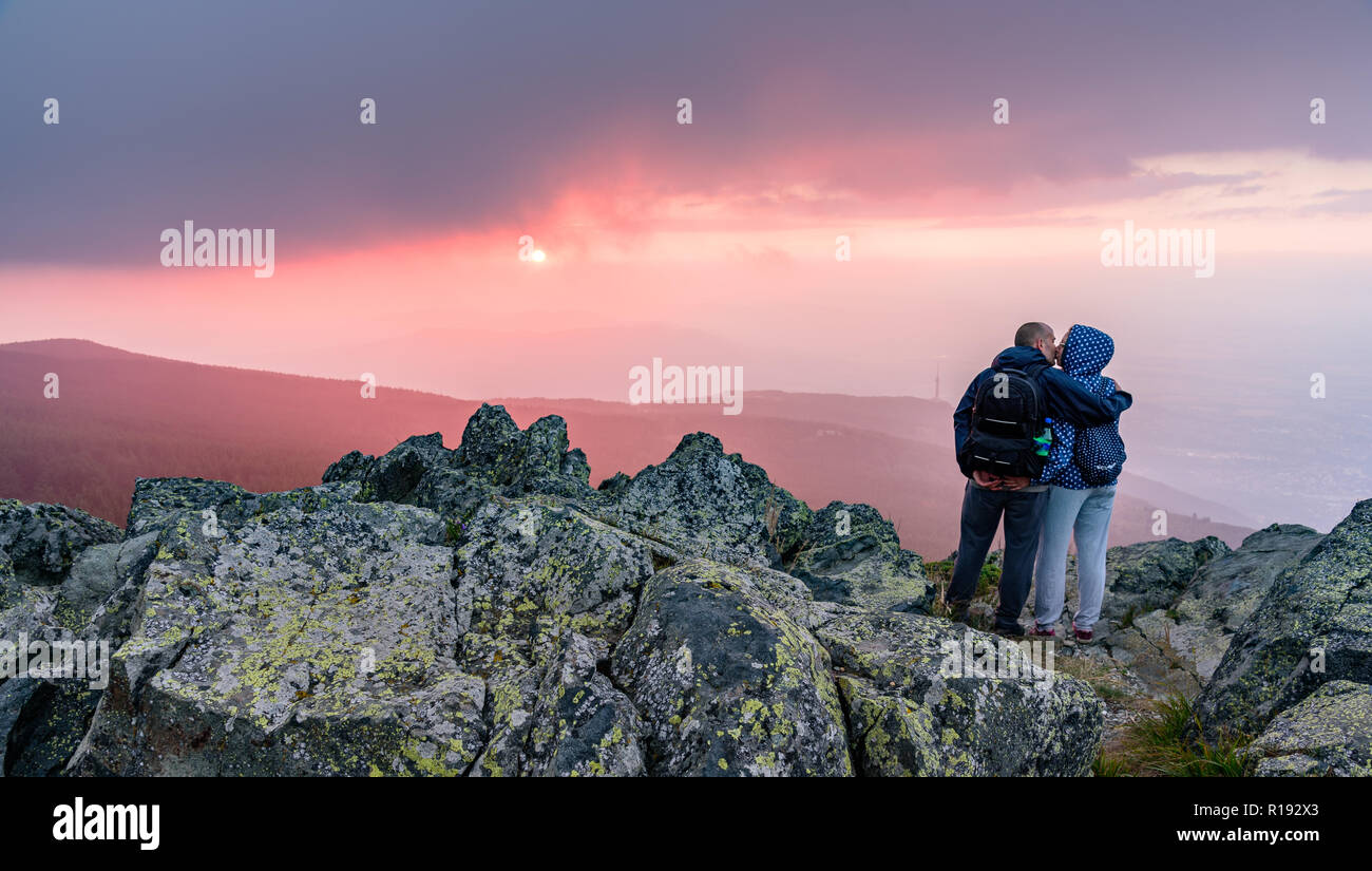 Week-end romantique européenne - un couple s'embrasser sur le sommet d'une montagne sous le soleil couchant Banque D'Images