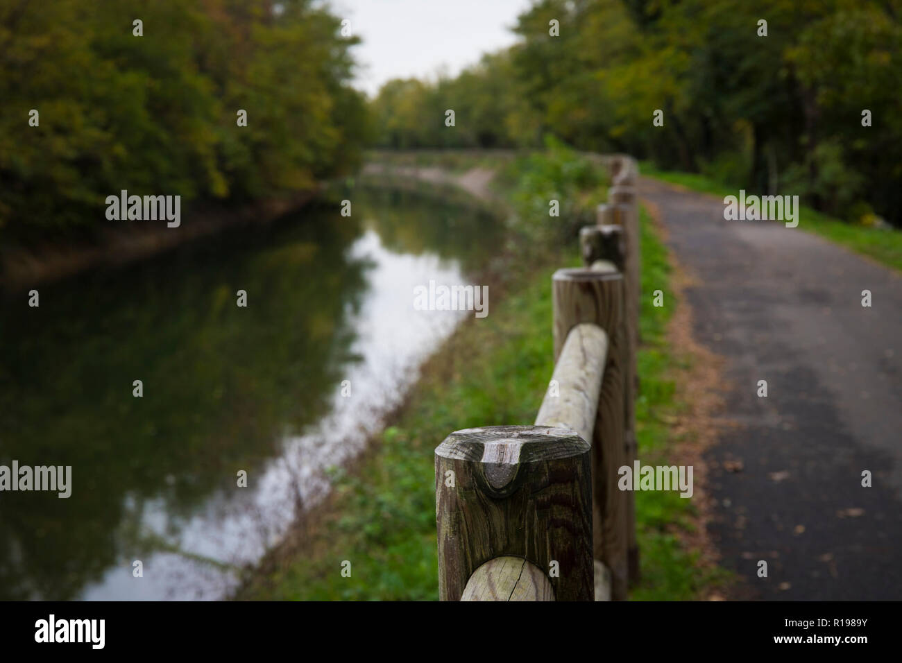 La voie vélo le long du canal Villoresi sur une journée d'automne. L'accent sur les poteaux de la clôture. Arconate, Italie. Banque D'Images