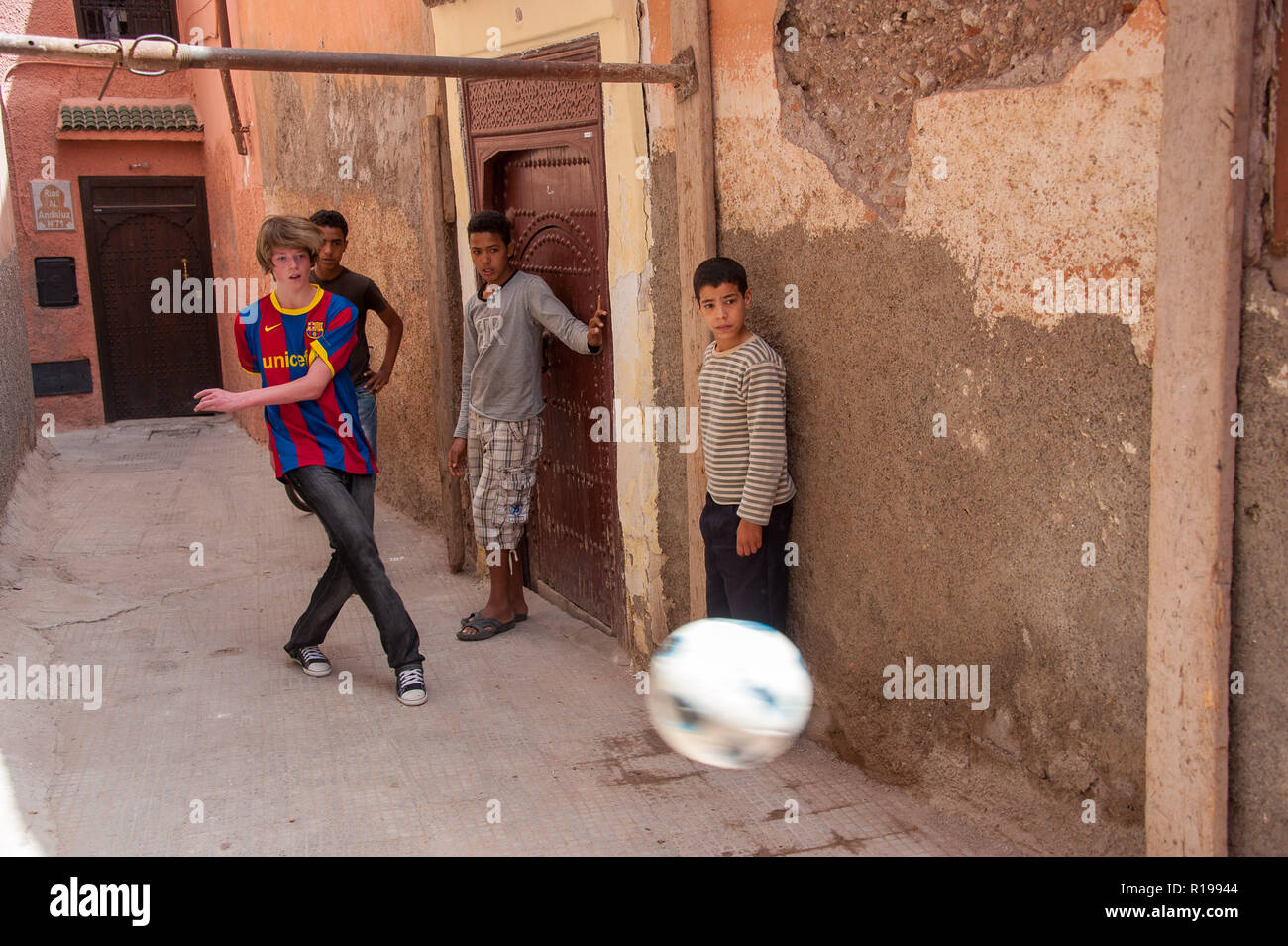 18-04-11. Marrakech, Maroc. Garçon anglais jouant au football avec les garçons marocains dans une ruelle dans la médina. Photo © Simon Grosset / Q Photography Banque D'Images