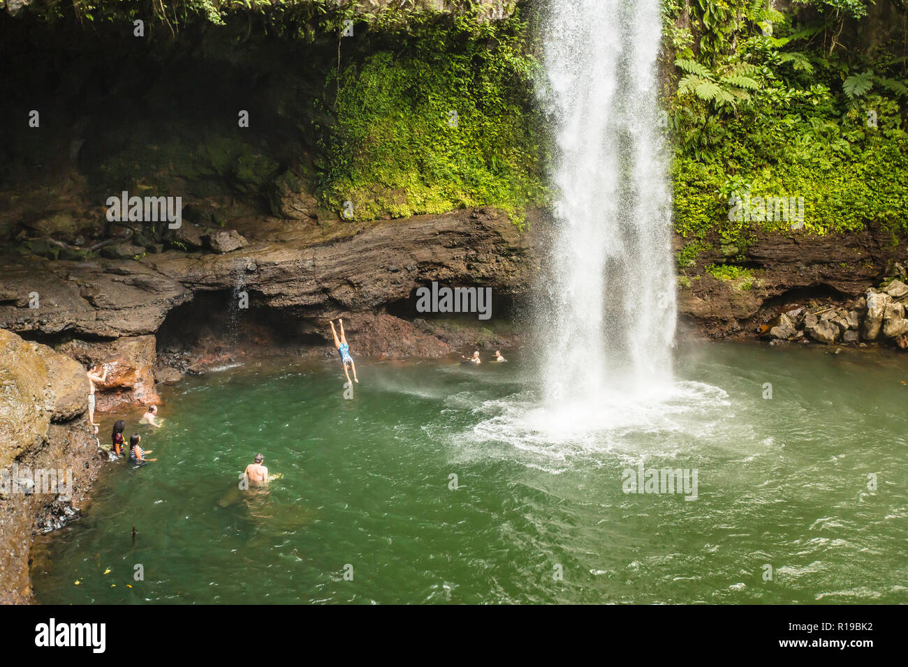 Les touristes profiter de la fraîcheur des eaux d'une cascade sur l'île de Taveuni, République de Fidji. Banque D'Images